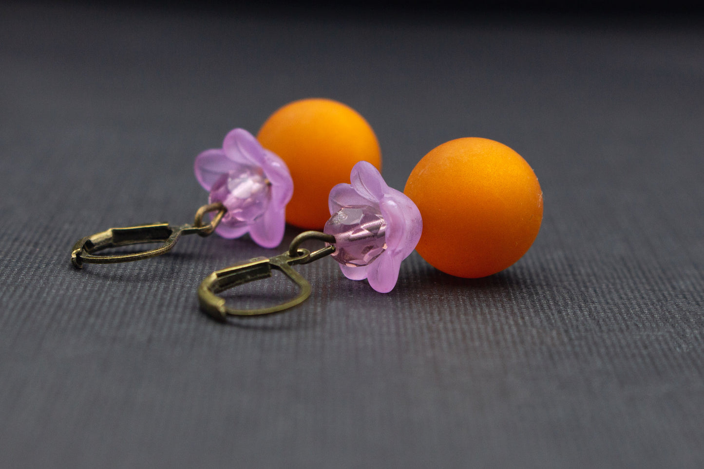 Nahaufnahme einer fliederfarbenen Blüte kombiniert mit hellbrauner Polaris-Perle, eleganter Ohrschmuck