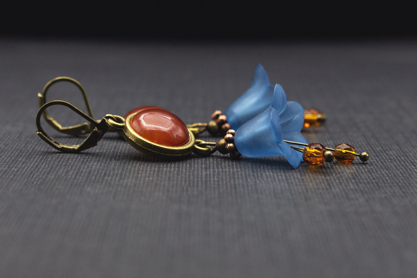 Detailaufnahme der Glasperlen und Acrylblüten der Ohrringe in Dunkelblau und Braun