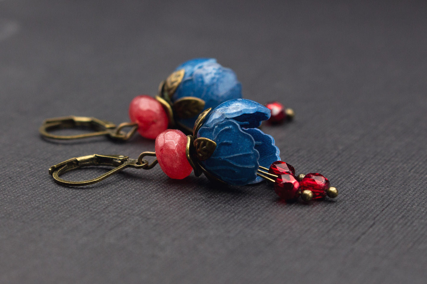 Detailaufnahme der Blütenohrringe in Blau mit roten und fuchsiafarbenen Perlen