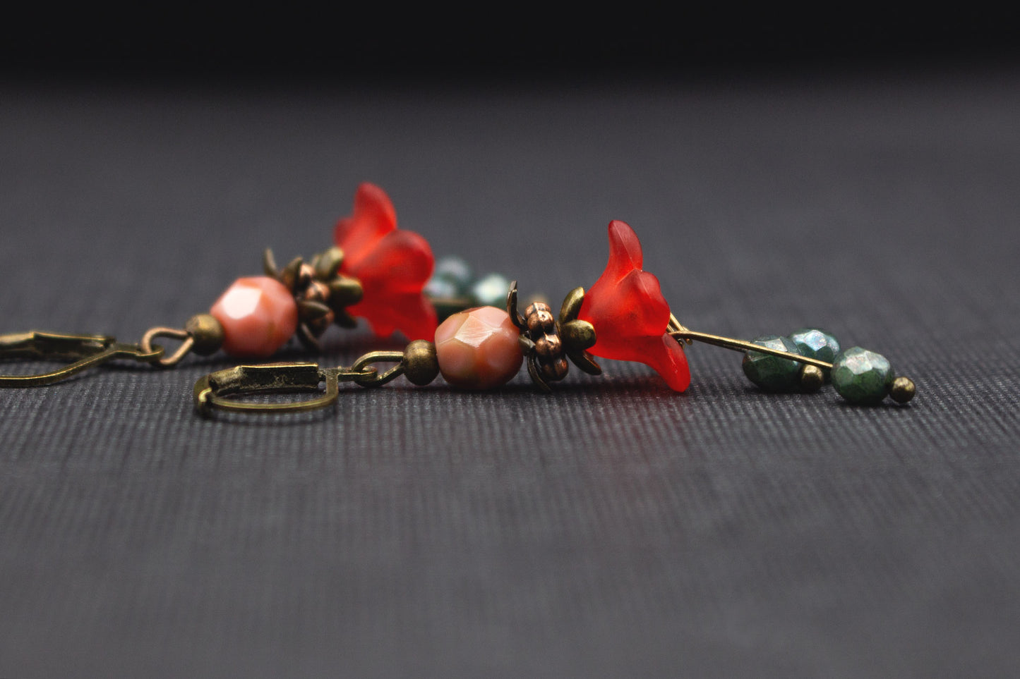 Seitliche Ansicht romantischer Blütenohrringe in Rot, Grün und Rosa mit Glasperlen