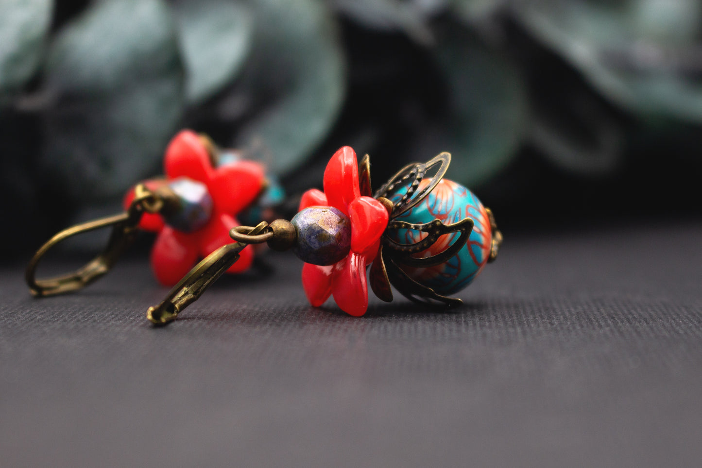 Ausdrucksstarke Rot-Türkis Ohrringe mit Blütenform, Glasperlen und Altbronze – modernes florales Schmuckdesign.