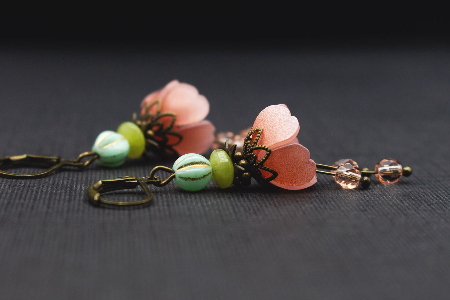 Seitenansicht von Boho Ohrringen mit Apricot-Rosa Acrylblüten und lindgrünen Perlen
