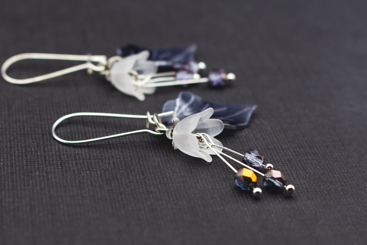 Seitliche Ansicht von Boho-Ohrringen mit weißen Acrylblüten und Perlen in Grau und Bronze