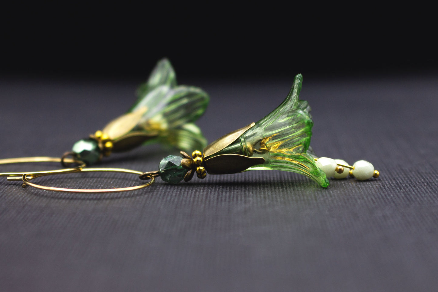Seitliche Ansicht von goldfarbenen Creolen Ohrringen mit grüner Acrylblüte und lindgrünen Glasperlen