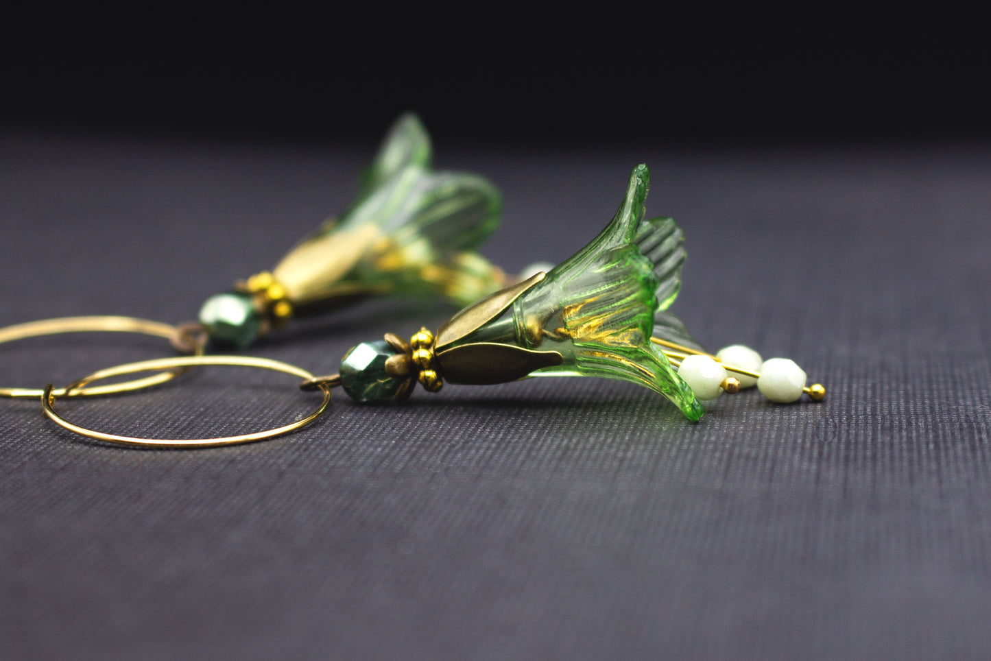Detailansicht goldfarbener Creolen Ohrringe mit grüner Acrylblüte und lindgrünen Glasperlen