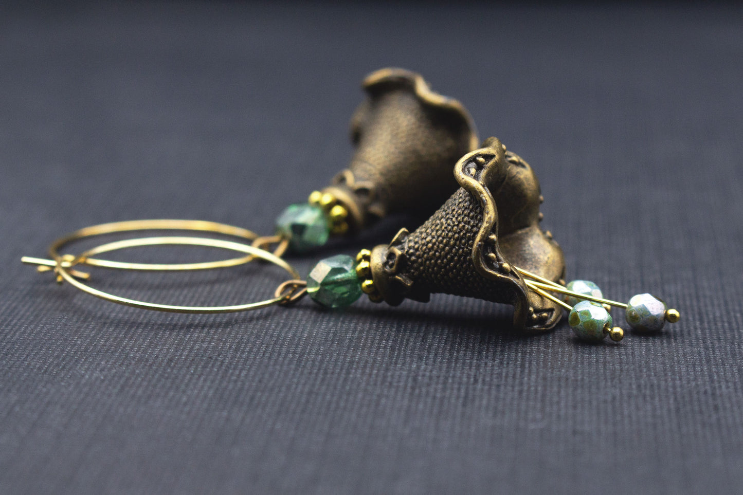 Seitenansicht von Creolen-Ohrringen mit Metallblüten in Antik-Bronze und Perlen in Grüntönen