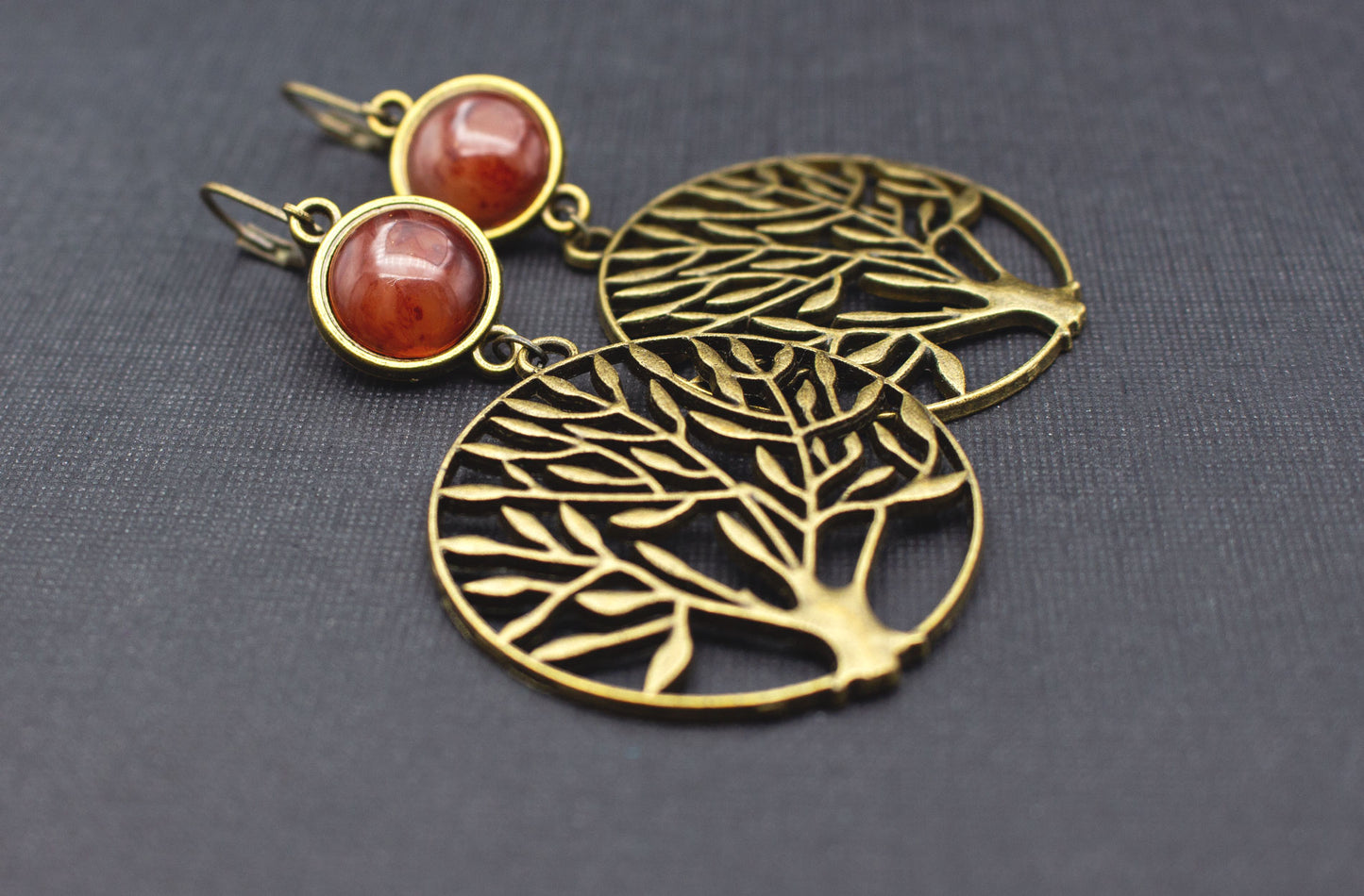 Detailaufnahme eines filigranen Baum-Anhängers mit Cabochon in warmem Bernsteinbraun