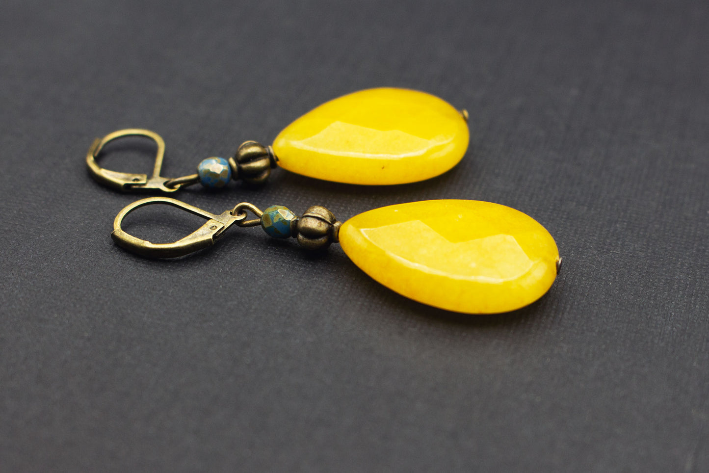 Detailansicht von gelben Tropfenperlen und petrolblauer Glasperle an antik bronzefarbenen Ohrringen