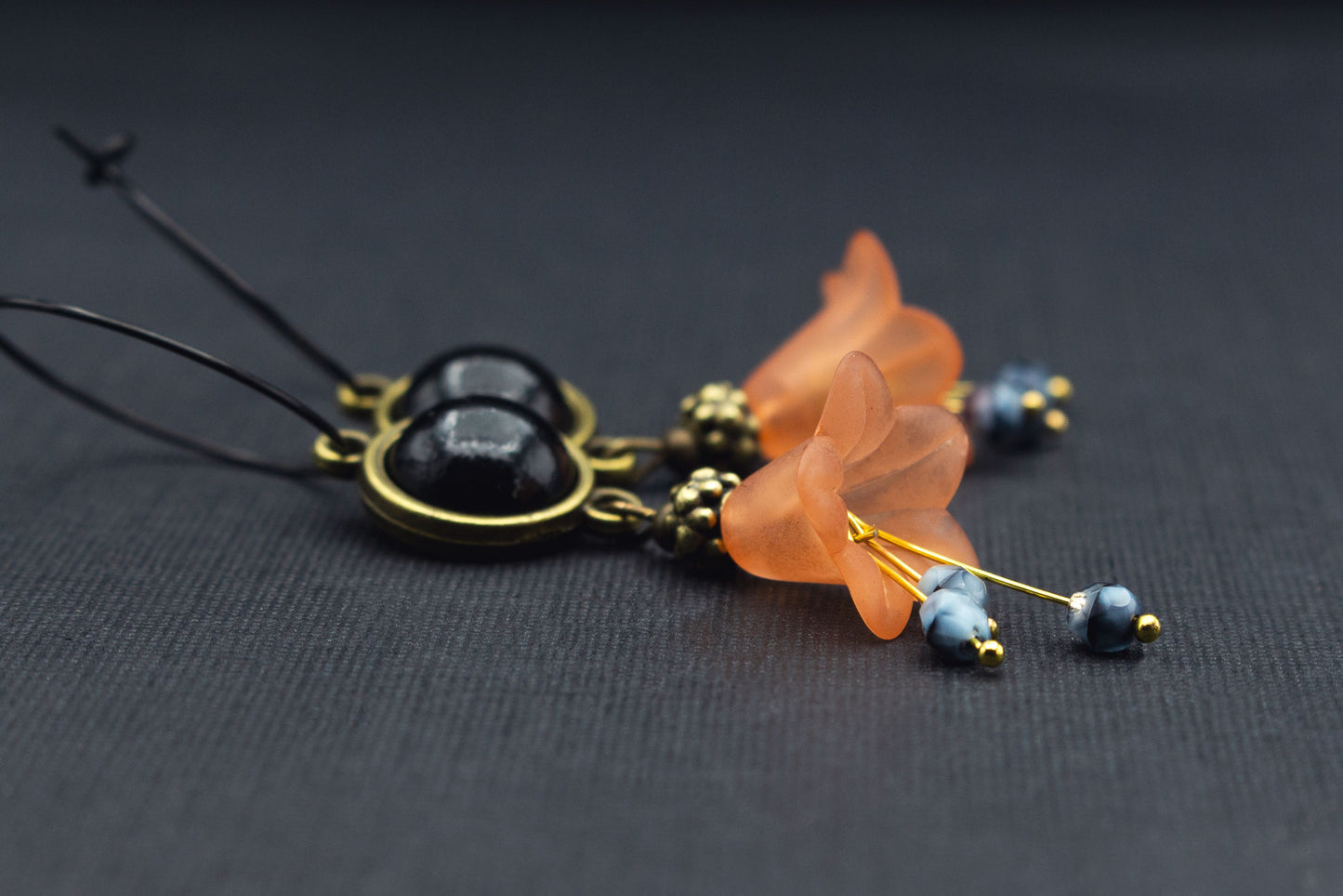 Detailansicht schwarze Creolen mit orangefarbenen Acrylblüten und Cabochon