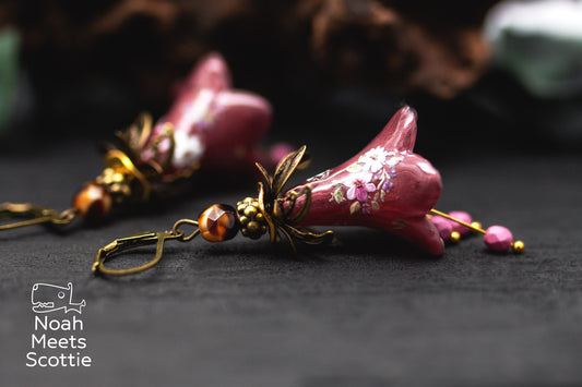 Handbemalte Blütenohrringe in Aubergine und Lila mit floralen Verzierungen und Glasperlen.