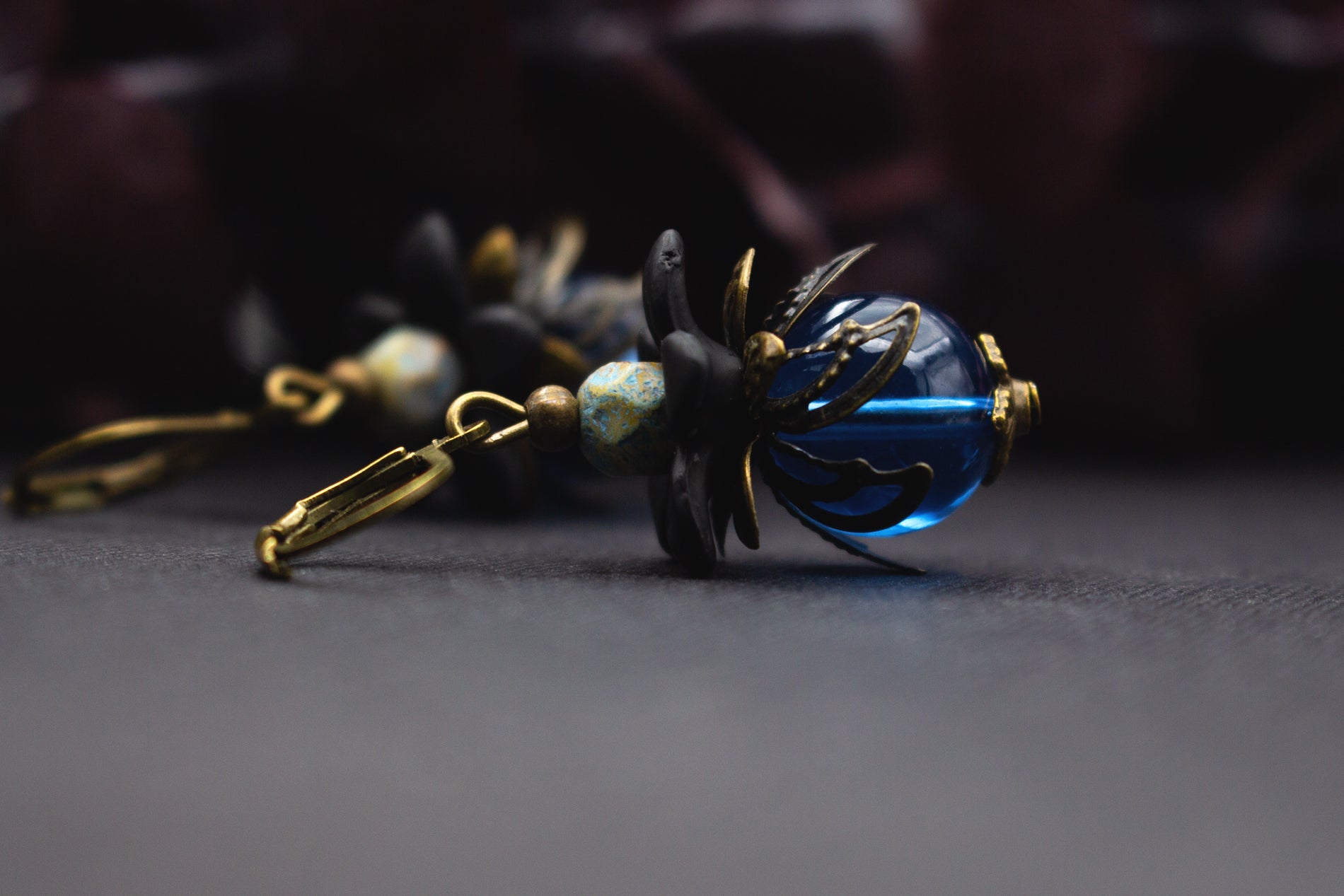 Handgefertigte Blütenohrringe Blau Schwarz mit facettierter Glasperle und schwarzer Blüte – markanter Schmuck für besondere Looks.