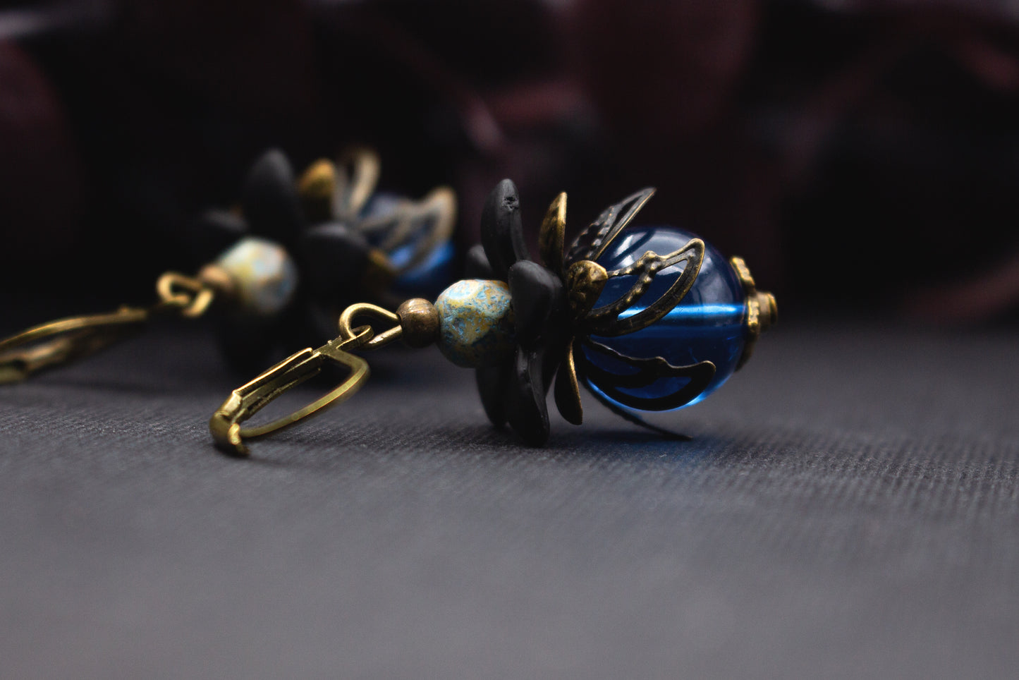 Ausdrucksstarke Blütenohrringe Blau Schwarz mit transparentem Glas und Bronze – kunstvoller Ohrschmuck für stilvolle Outfits und Geschenke.