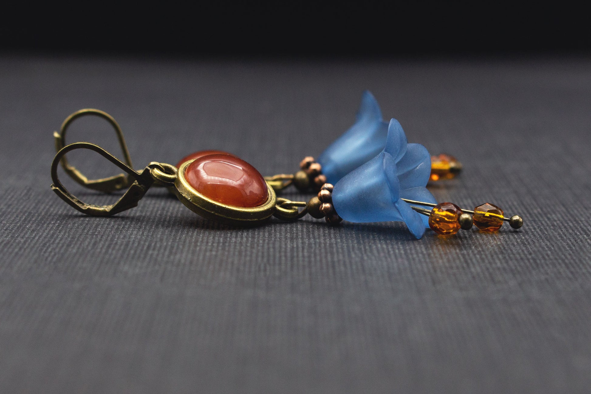Detailaufnahme der Glasperlen und Acrylblüten der Ohrringe in Dunkelblau und Braun