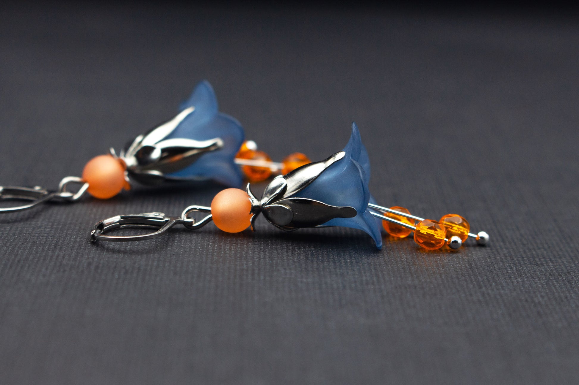 Detailaufnahme von Blütenohrringen in Dunkelblau und Orange mit Glasperlen
