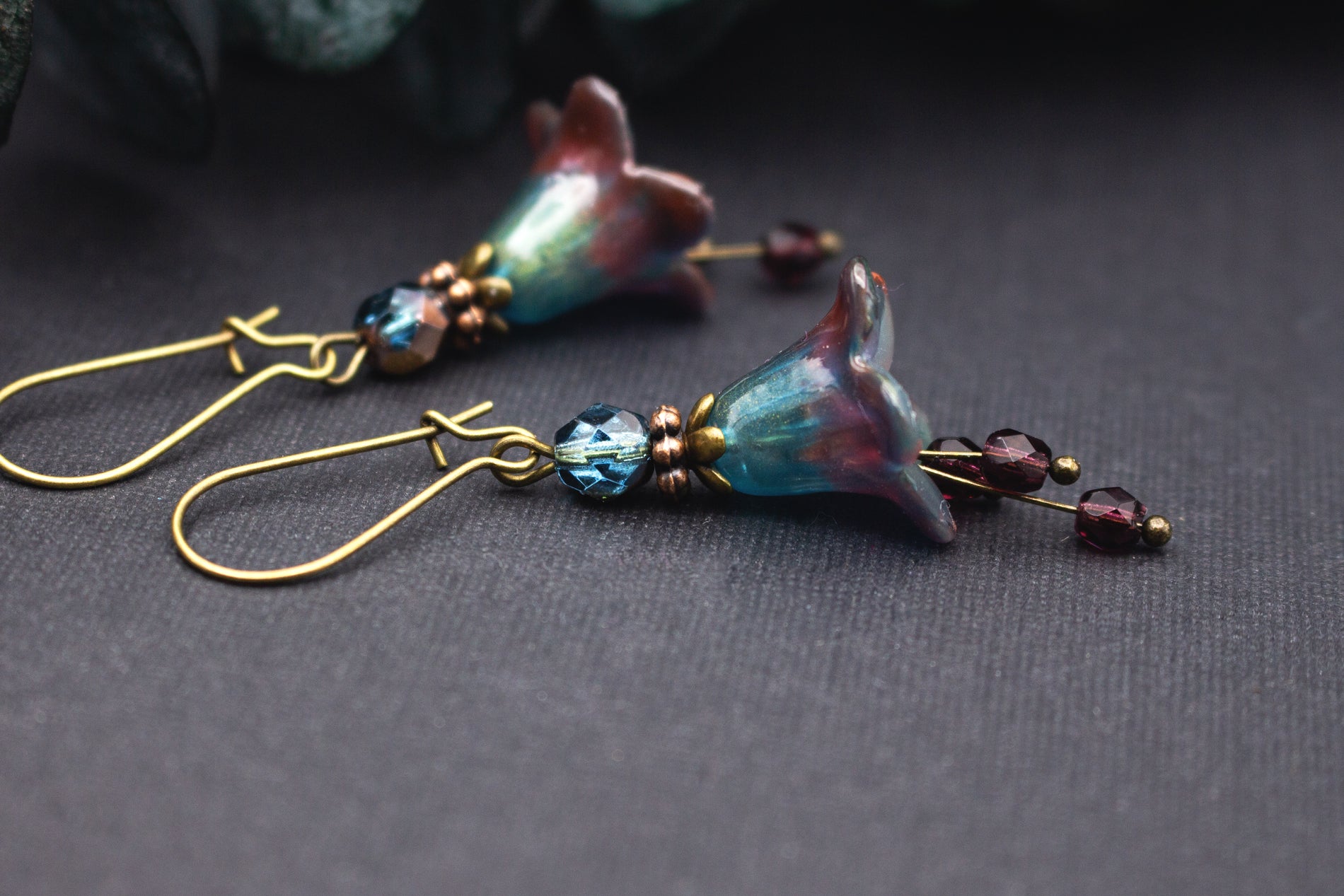 Detailansicht handbemalter Blütenohrringe in Dunkelrot und Petrolblau mit Farbverlauf