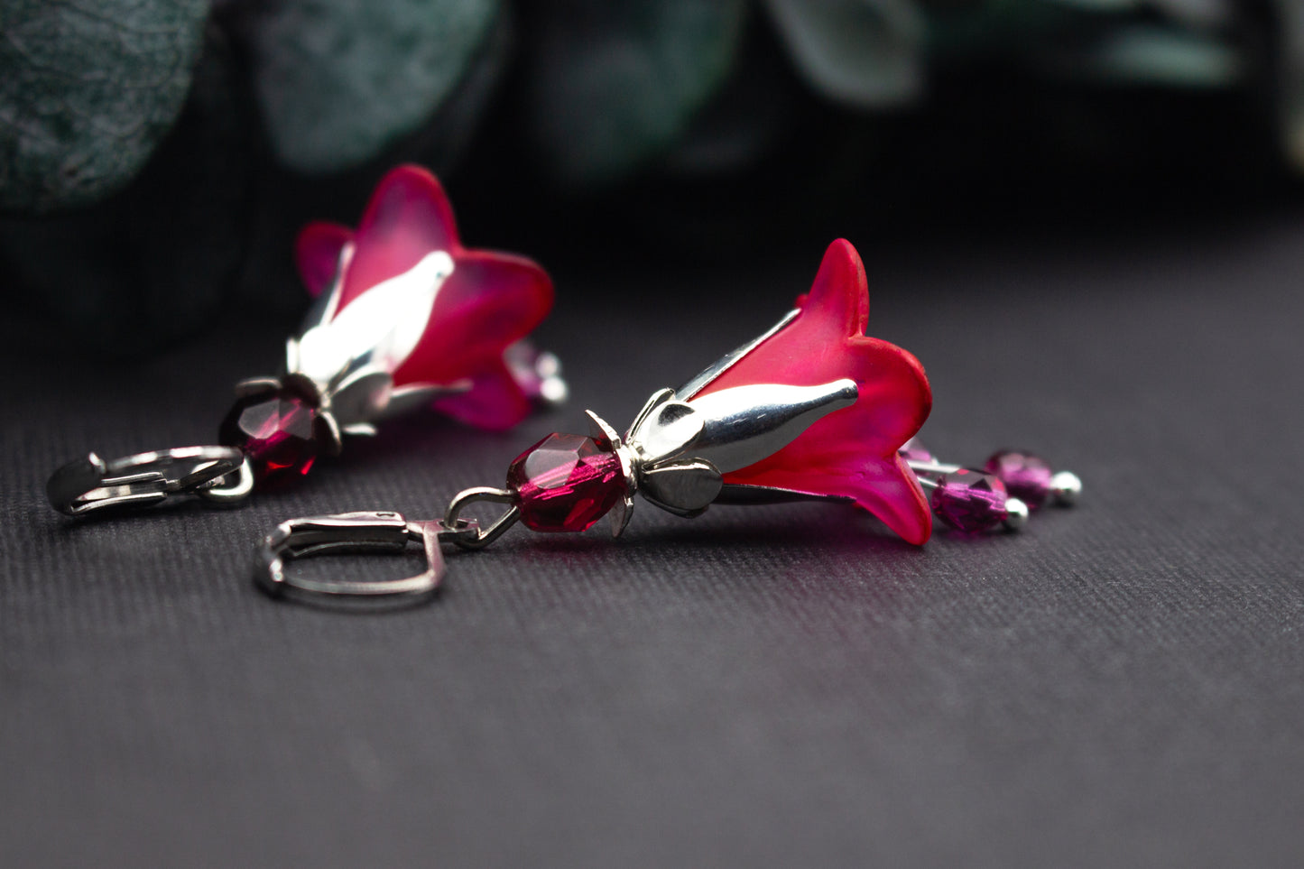 Detailaufnahme von floralen Ohrringen mit pinker Blüte und facettierten Glasperlen in Silberfassung