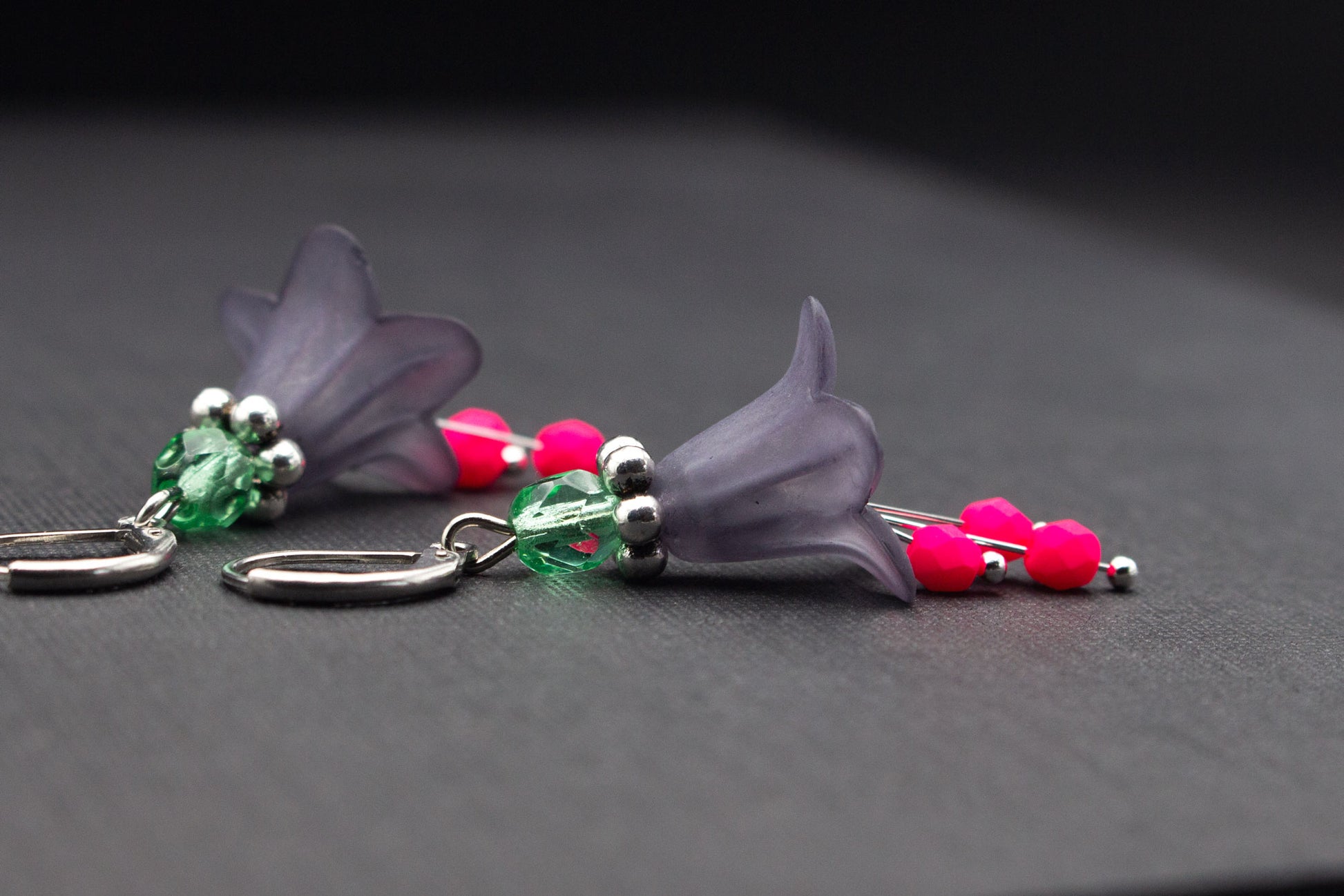 Seitliche Ansicht grauer Blütenohrringe mit Glasperlen in Mint und Neonpink