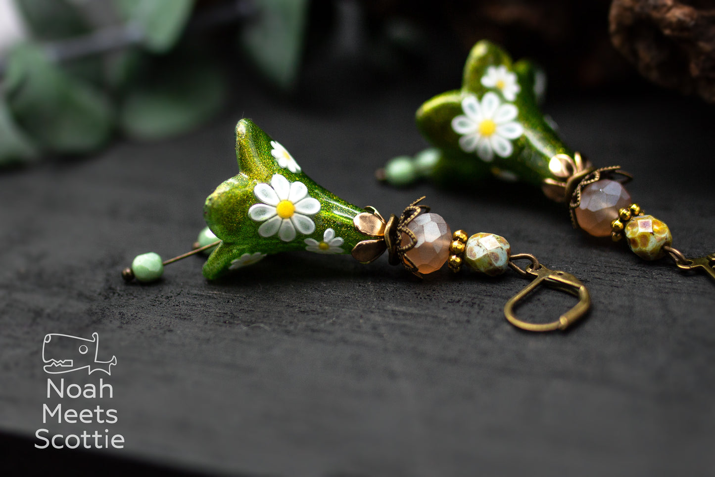 Florale Ohrringe mit großen grünen Blüten, bronzefarbenen Fassungen und abgestimmten Glasperlen.