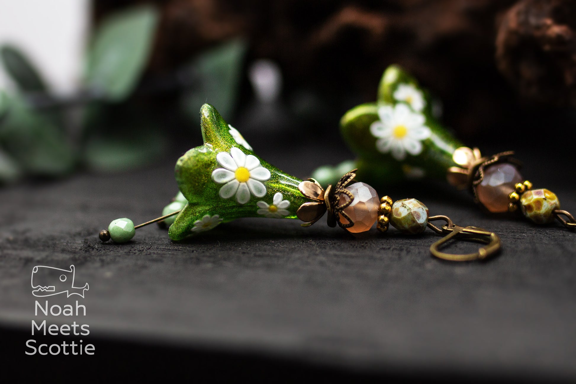 Seitenansicht der handgefertigten Blütenohrringe mit schimmernden grünen Blüten und kleinen Margeriten.