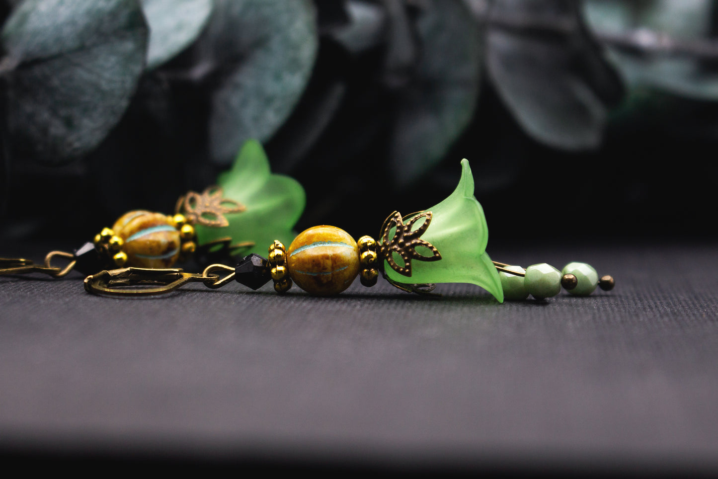 Acrylblüte in Hellgrün mit bronzefarbenem Blätterdetail und Glasperlen – leichter, natürlicher Ohrschmuck.