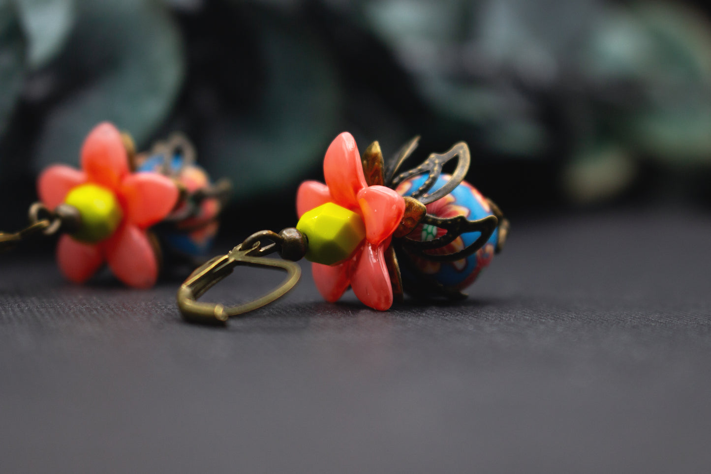 Leichte Ohrhänger mit lachsrosa Blüten, blauer Blumenperle und gelben Akzenten, farbenfroher Schmuck für Alltag und besondere Anlässe.