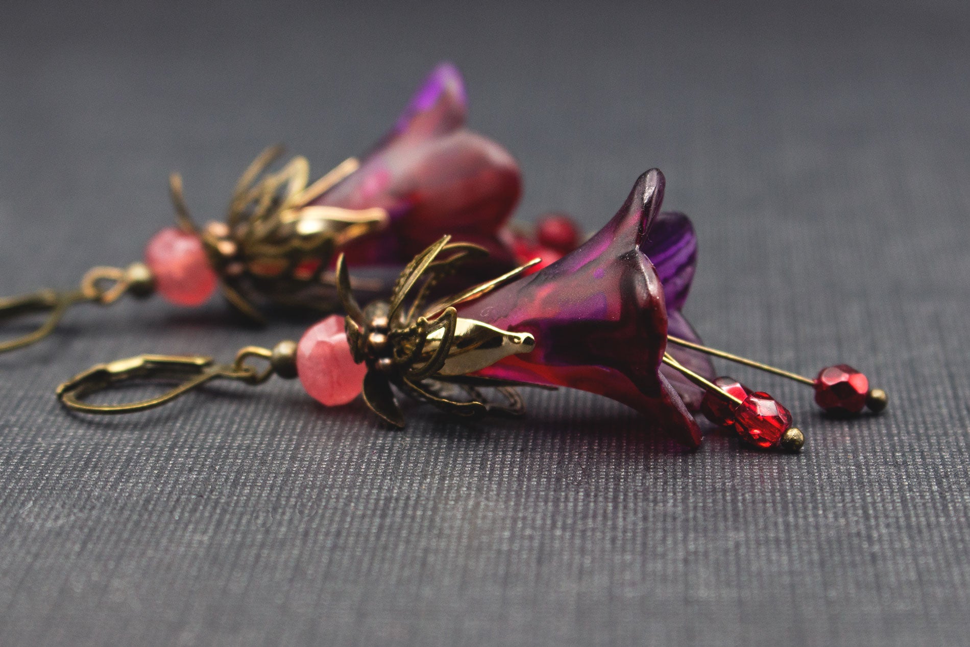 Detailansicht romantische Ohrringe mit lila Blüten, tiefroten Elementen und Flamingo-Pink