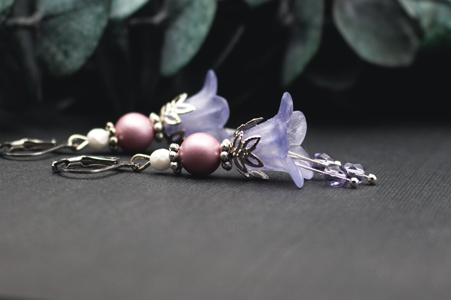 Lila-weiße Glasperlenohrringe mit silbernen Ornamenten und transparenten Acrylblüten – filigraner Ohrschmuck im winterlich eleganten Stil.