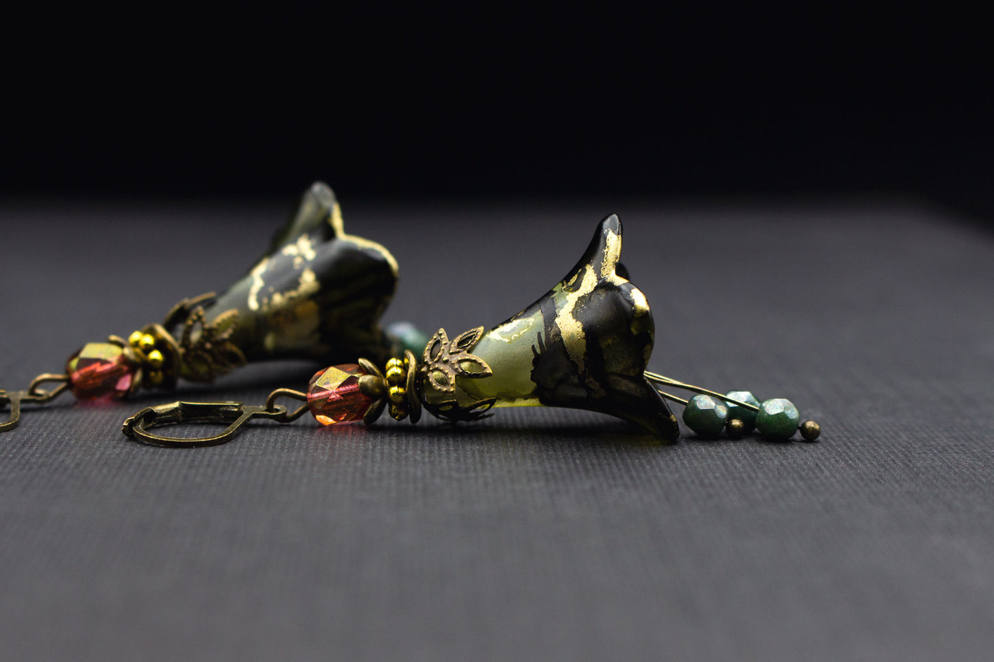 Ausdrucksstarke Ohrringe mit Blüten in Olivgrün, Schwarz und goldenen Details