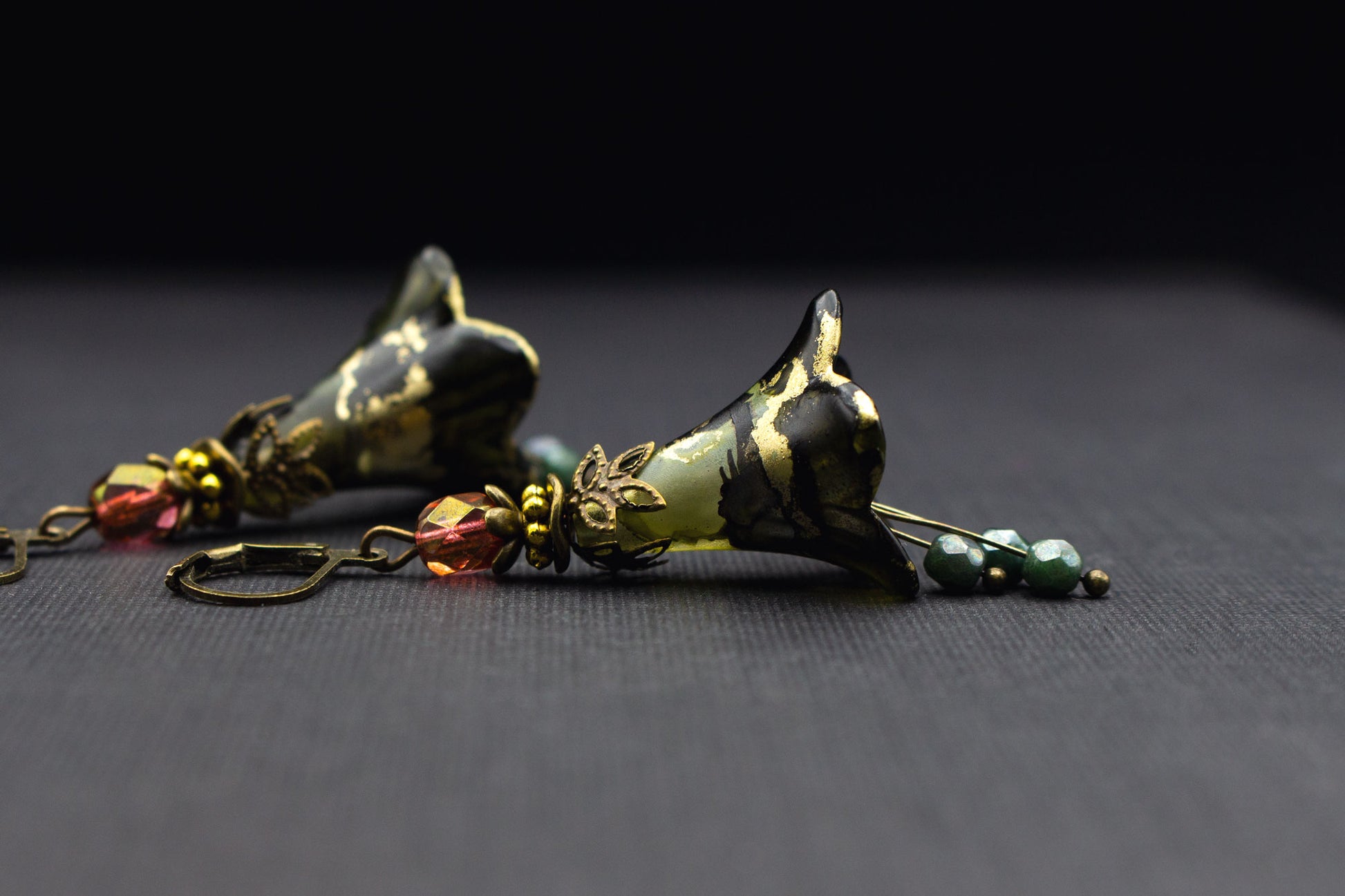 Ausdrucksstarke Ohrringe mit Blüten in Olivgrün, Schwarz und goldenen Details