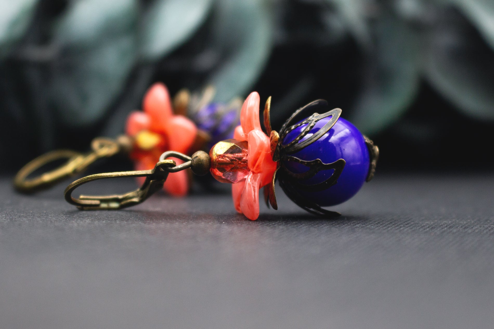 Florale Vintage-Ohrringe in Orange und Blau mit Glasperle und Bronze – kunstvoller Schmuck mit klarer, lebendiger Farbwirkung.