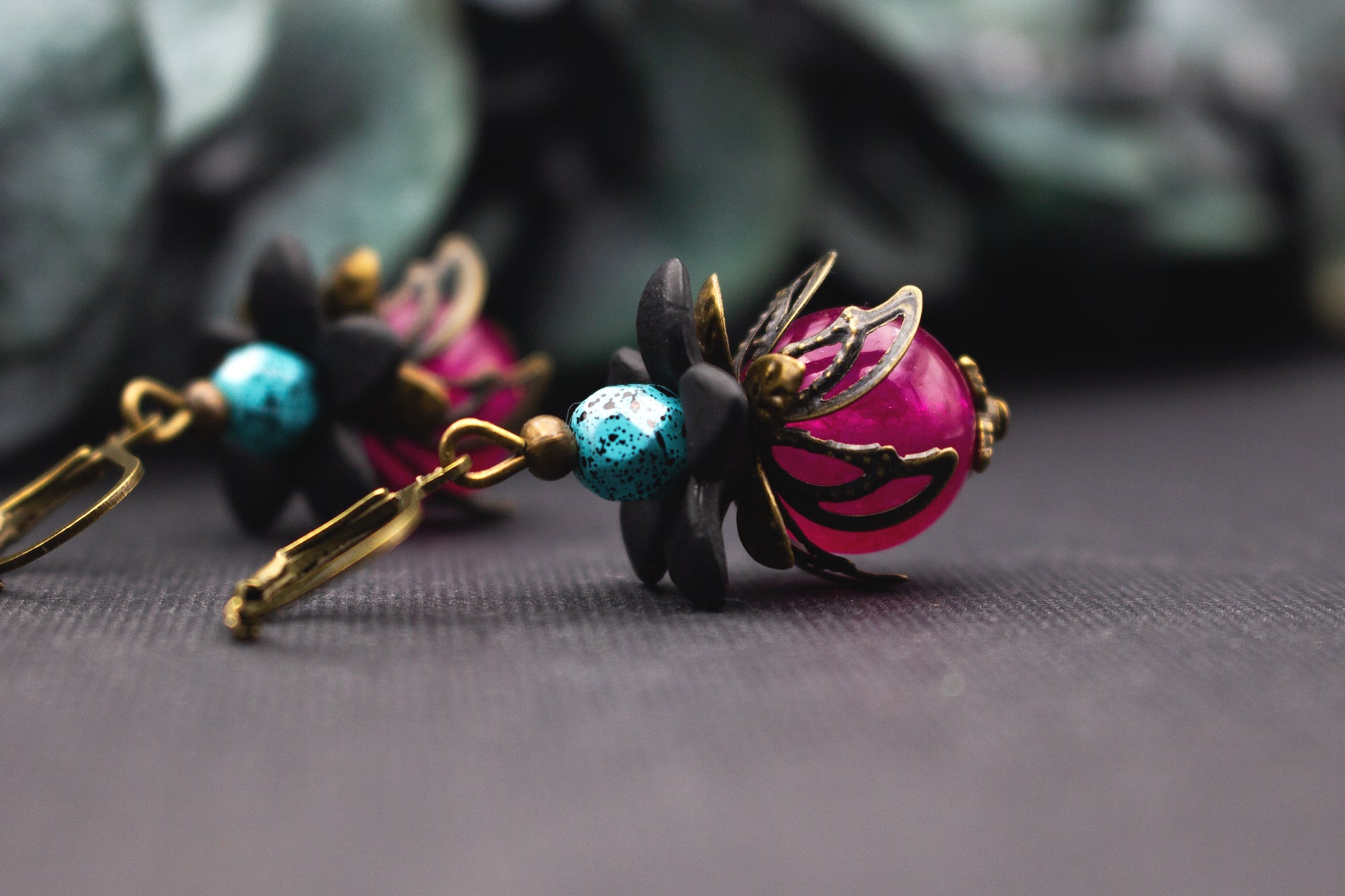 Ausdrucksstarke Blütenohrringe Pink Schwarz Türkis mit Glasperlen und Bronze – farbintensiver Ohrhänger mit floralen Details.
