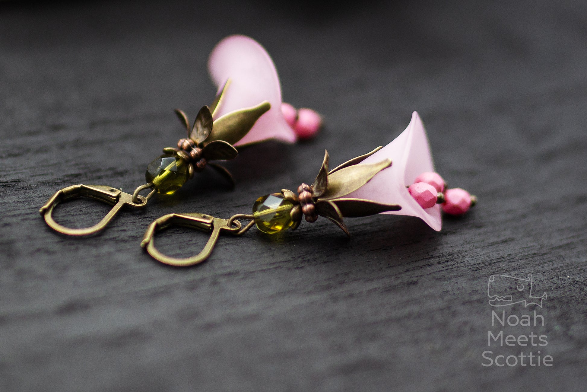 Blütenohrringe rosa mit bronzefarbenen Details auf dunklem Hintergrund