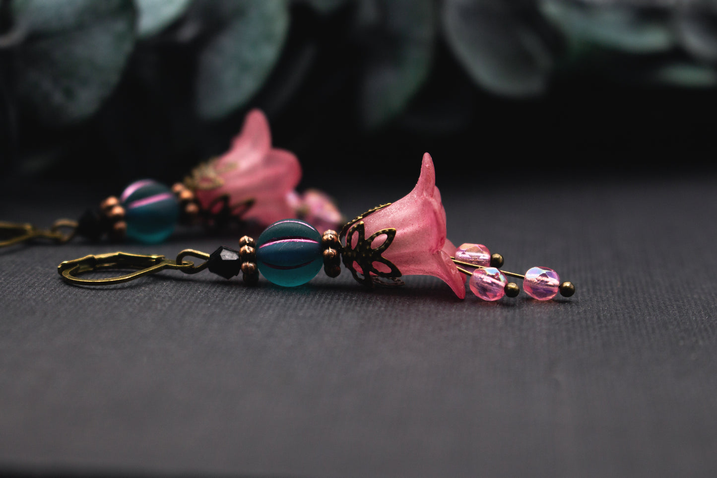 Florale Rosa-Petrol Ohrringe mit zarter Blütenglocke, facettierter Glasperle und bronzenen Details – feminine Ohrhänger mit sanfter Bewegung.