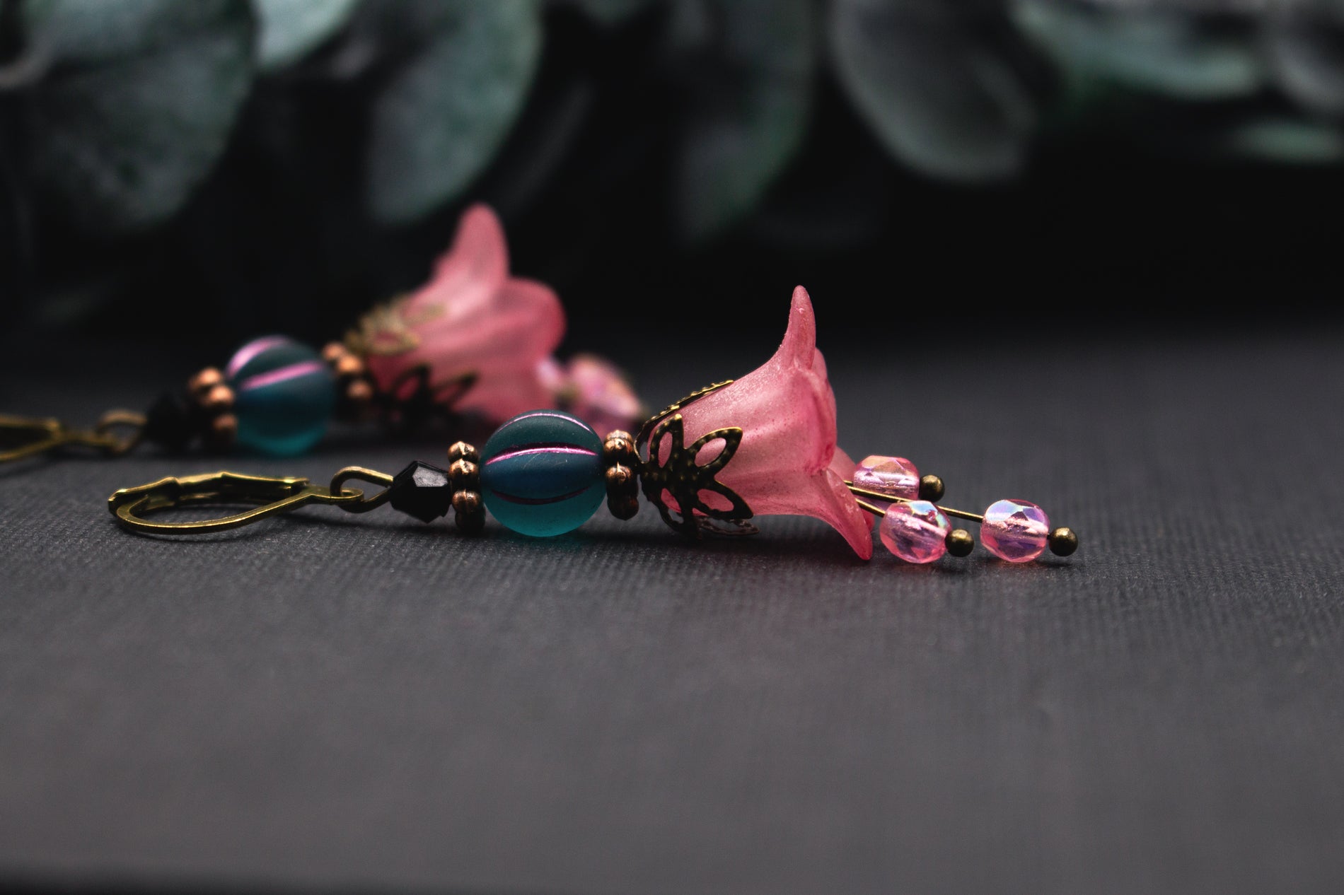 Florale Rosa-Petrol Ohrringe mit zarter Blütenglocke, facettierter Glasperle und bronzenen Details – feminine Ohrhänger mit sanfter Bewegung.
