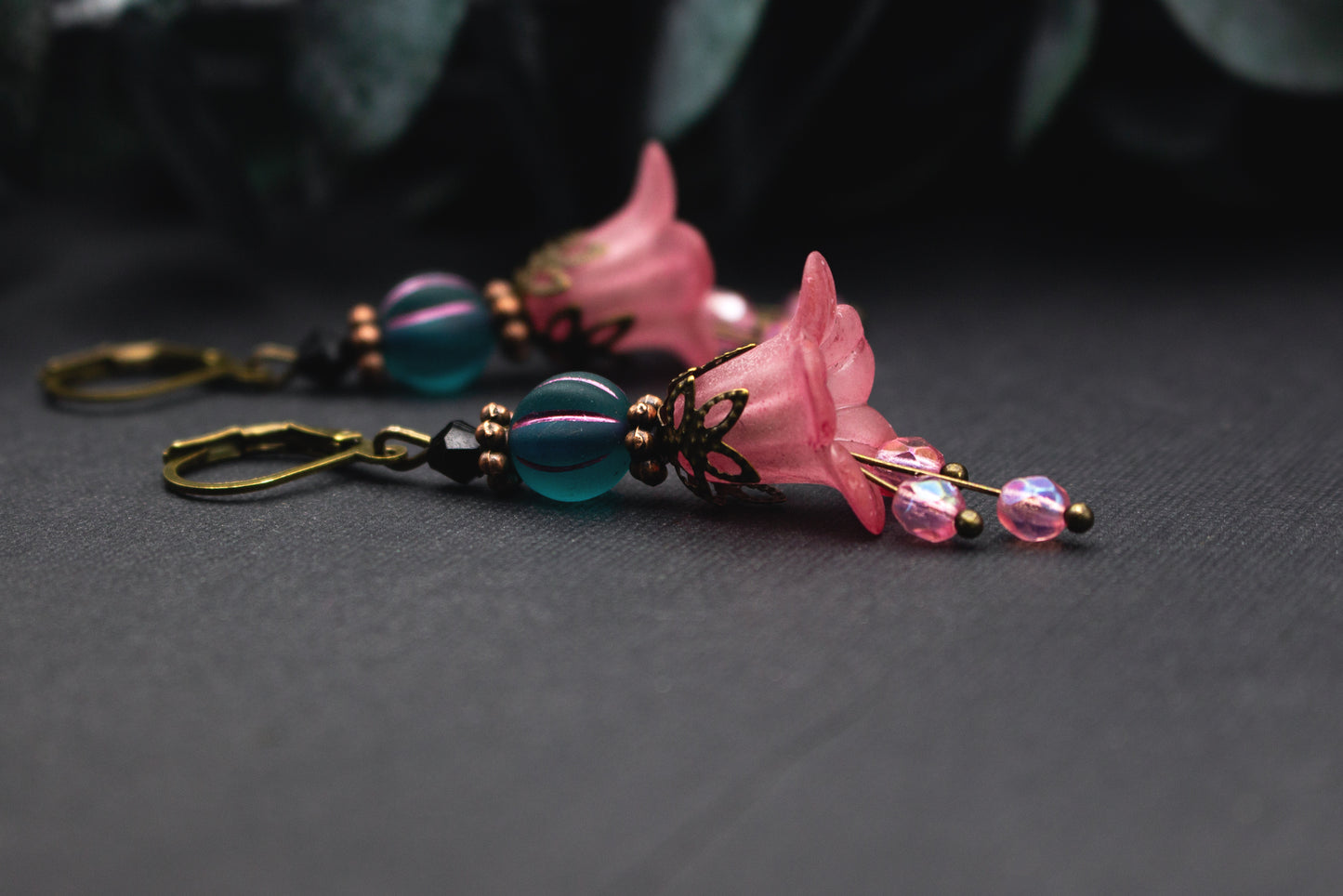 Rosa-Petrol Blütenohrringe mit transparenter Acrylblüte, petrolfarbener Glasperle und Bronzeakzenten – leichter, harmonischer Ohrschmuck mit weichem Farbverlauf.