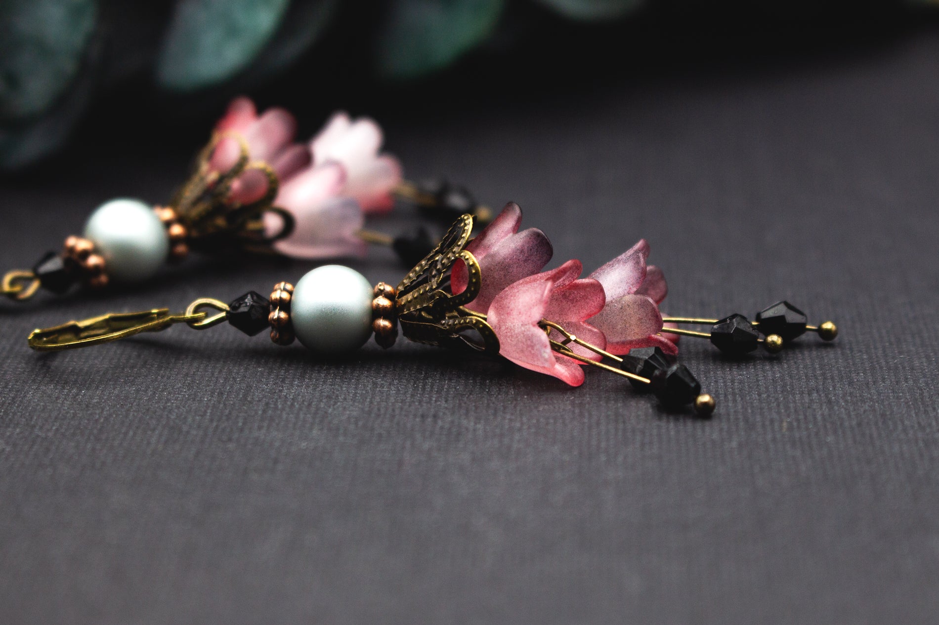 Rosé-Mauve Blumenohrringe mit facettierten schwarzen Glasperlen und bronzenen Details – feminine, kunstvolle Vintage-Ohrringe.