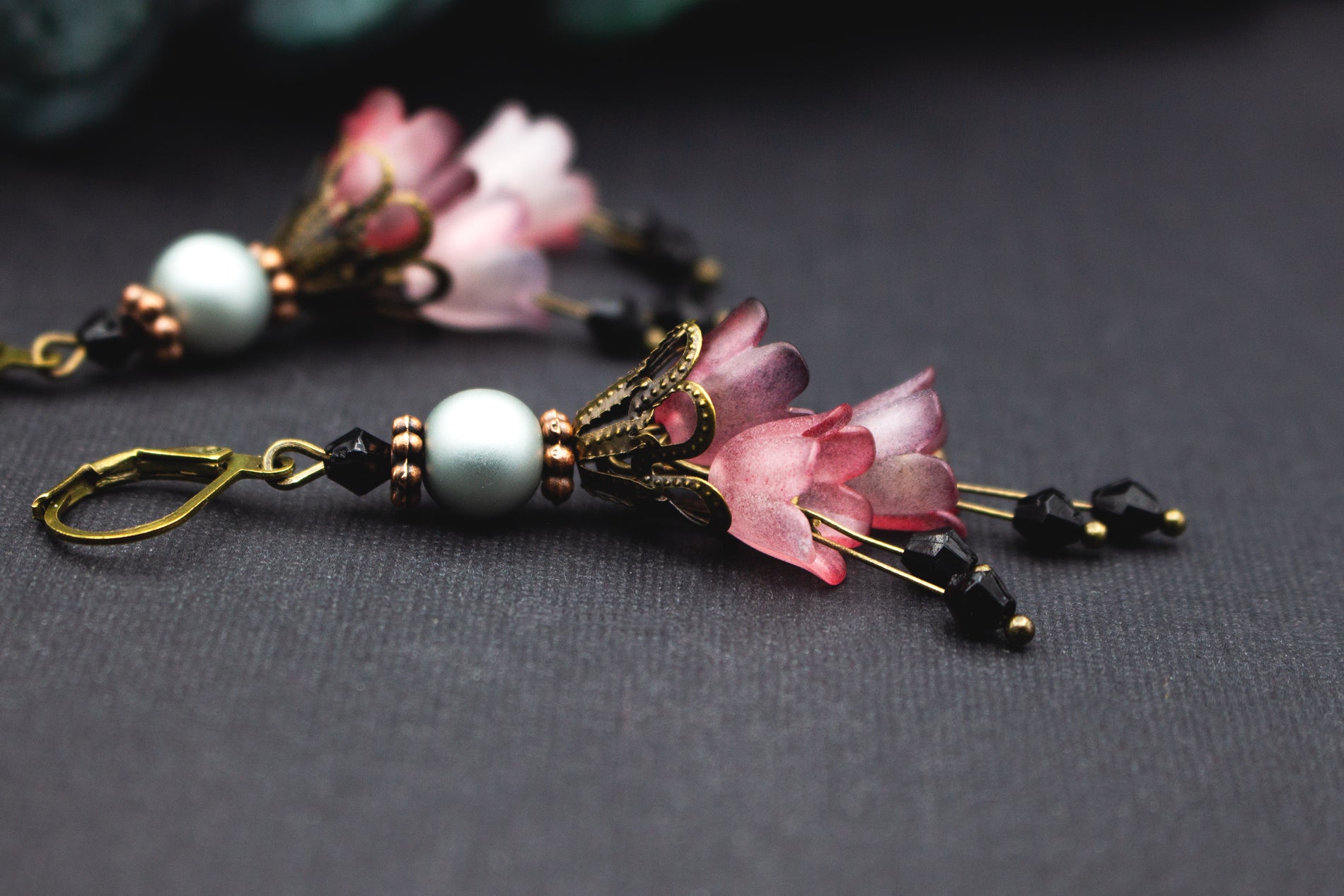 Blütenohrringe in Rosé und Mauve mit perlweißer Perle, schwarzen Glasakzenten und Bronze – eleganter floraler Vintage-Schmuck.