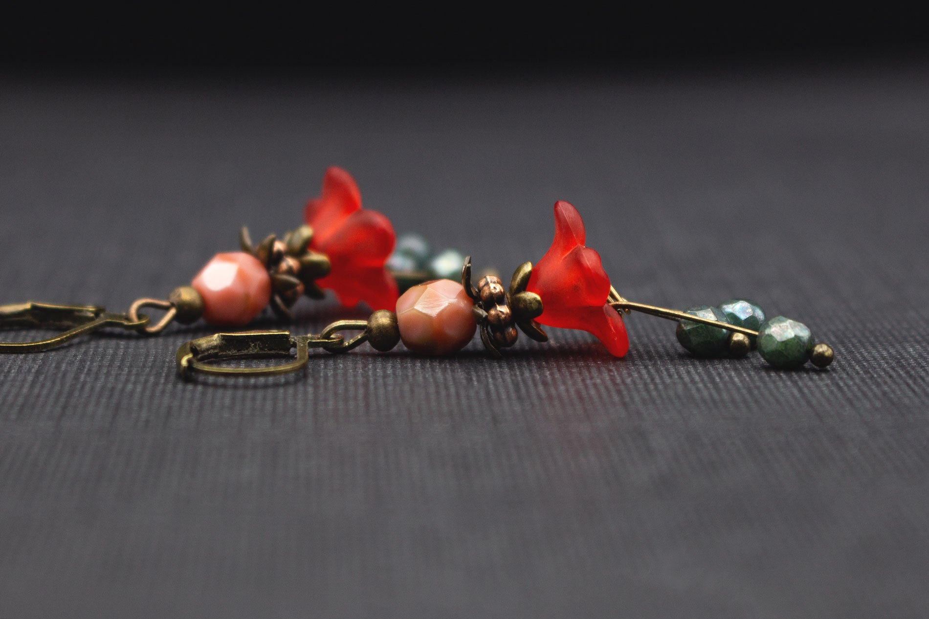 Seitliche Ansicht romantischer Blütenohrringe in Rot, Grün und Rosa mit Glasperlen