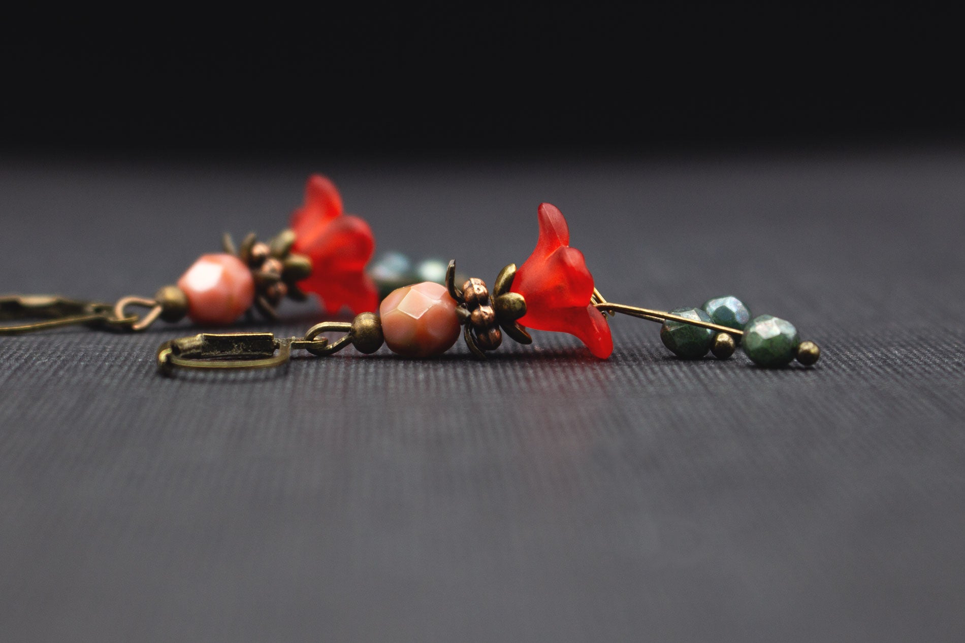 Detailaufnahme von Acrylblüten in Rot, Grün und Rosa mit Glasperlen und antik-bronzefarbenen Elementen