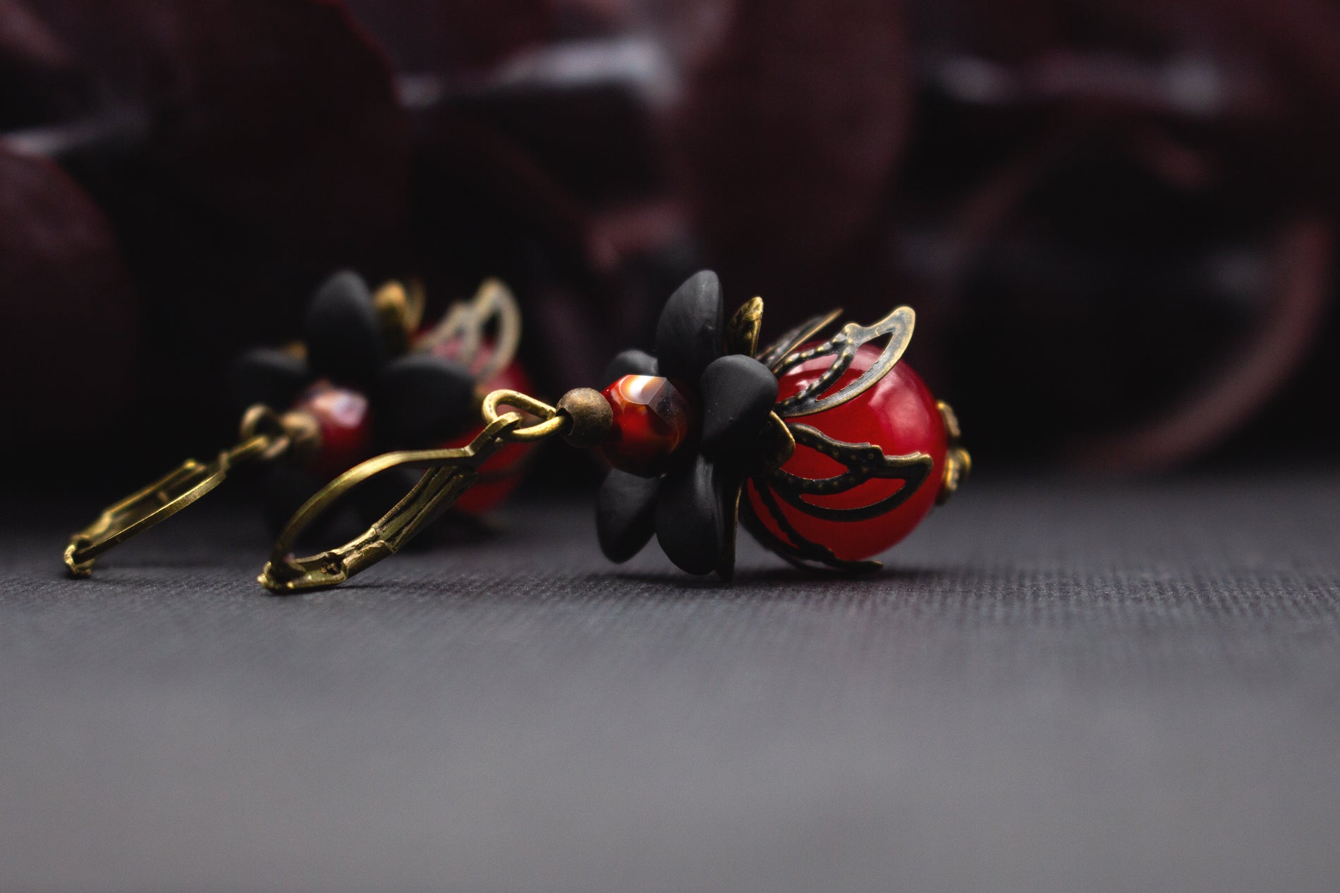 Rote Vintage-Blütenohrringe mit schwarzer Acrylblüte und warmen Bronzeelementen, ideal für elegante Anlässe und ausdrucksstarke Looks.