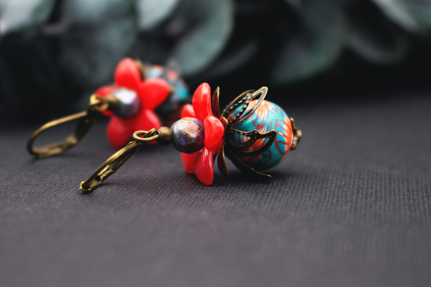 Blütenohrringe in Rot und Türkis mit gemusterter Glasperle und Bronze – farbintensiver floraler Vintage-Schmuck mit ausdrucksstarker Wirkung.