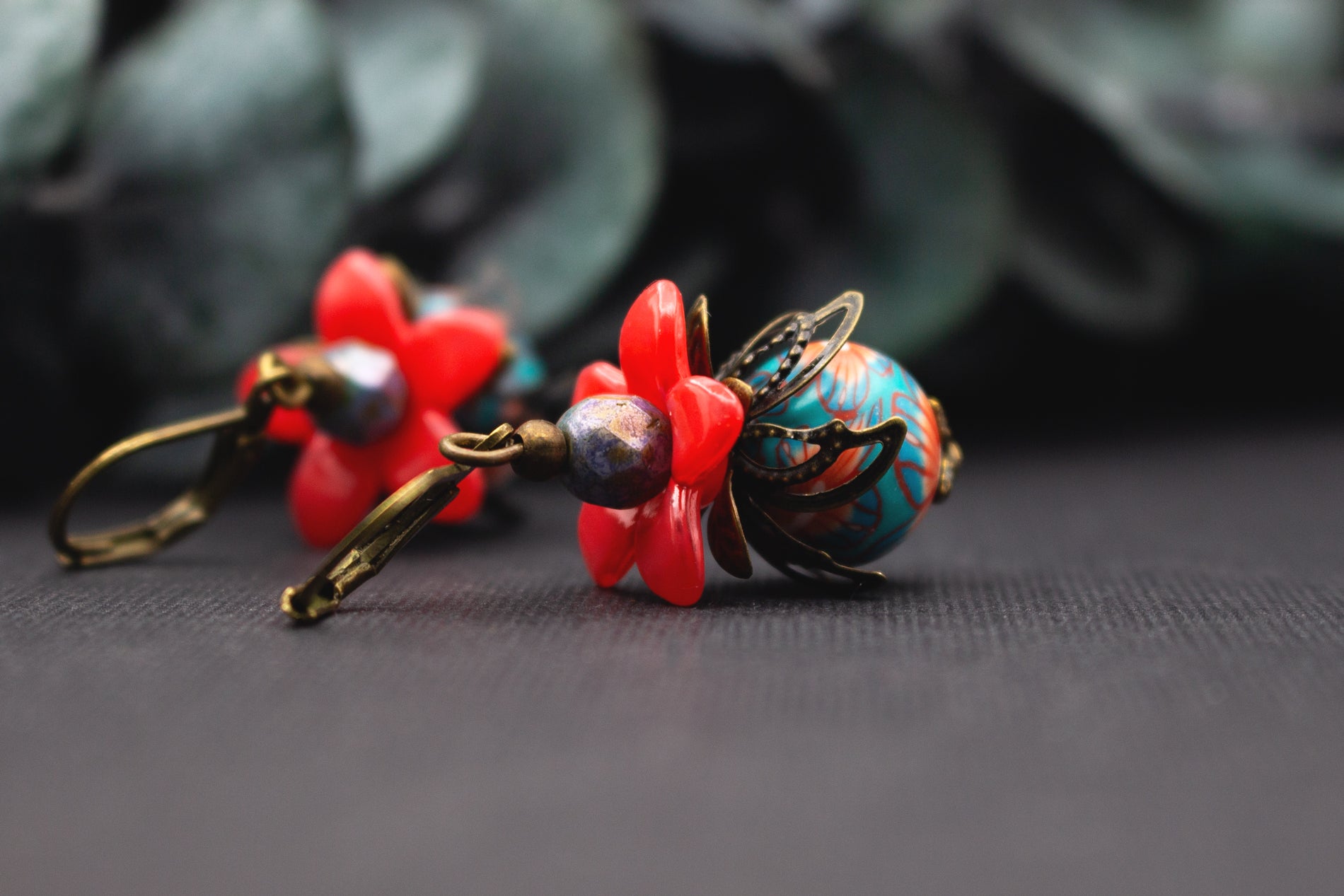 Ausdrucksstarke Rot-Türkis Ohrringe mit Blütenform, Glasperlen und Altbronze – modernes florales Schmuckdesign.