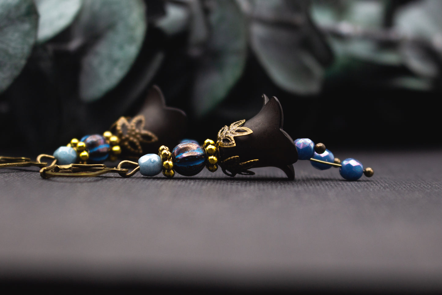 Schwarze Blütenohrringe mit blauen facettierten Perlen und goldfarbenen Details im Vintage-Stil