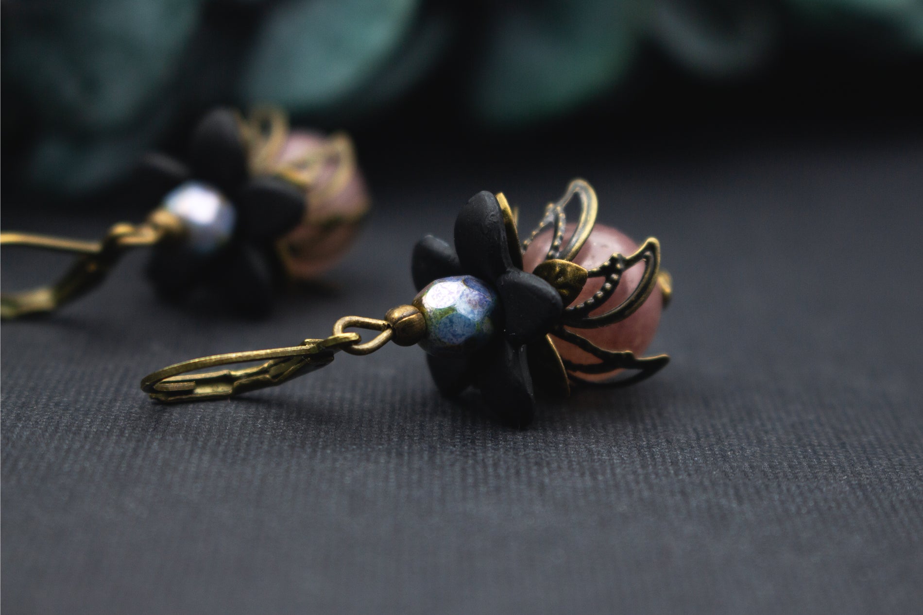 Schwarze Blumenohrringe mit roséfarbener Glasperle und bronzener Blütenkappe – kunstvoller, femininer Vintage-Ohrschmuck.