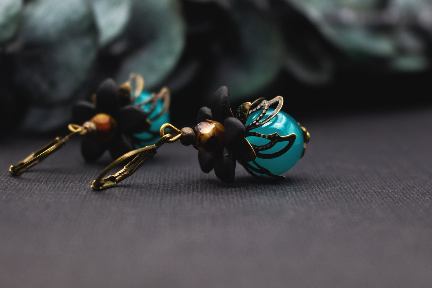Ausdrucksstarke Türkis-Glasperlen-Ohrringe mit schwarzen Blüten und Bronze – stilvoller floraler Schmuck im hochwertigen Vintage-Look.