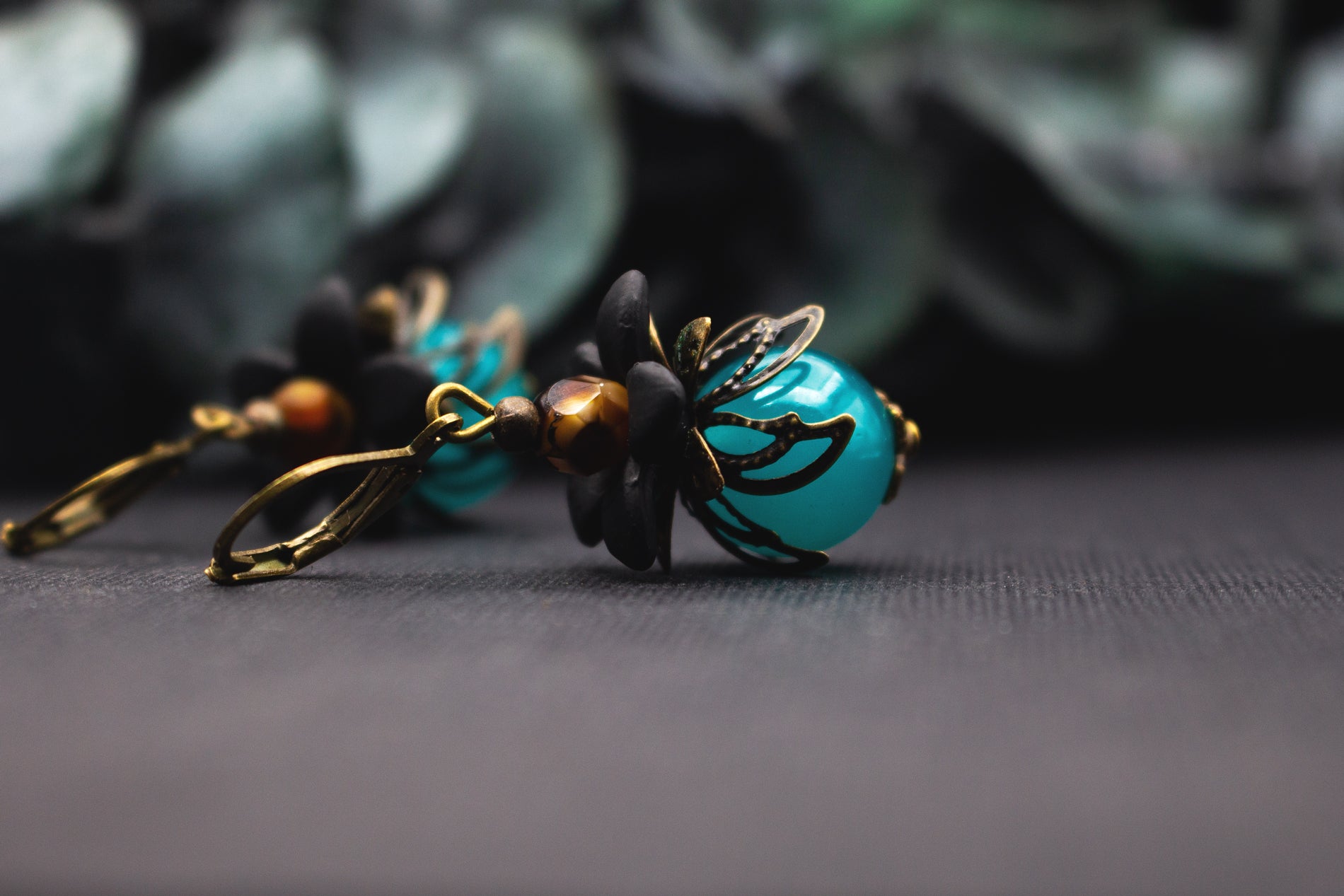 Vintage-Blütenohrringe in Türkis und Schwarz mit bronzenem Metall – detailreicher floraler Ohrhänger mit warmem Bernsteinakzent.