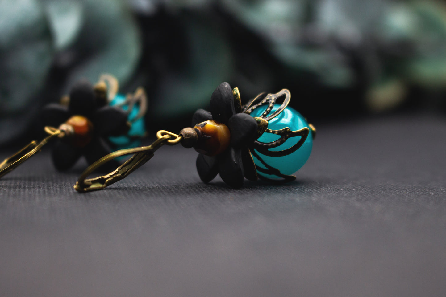 Florale Türkis-Ohrringe mit schwarzen Acrylblüten, Bernstein-Akzentperle und Bronze – kunstvoller Ohrhänger im ausdrucksstarken Vintage-Stil.