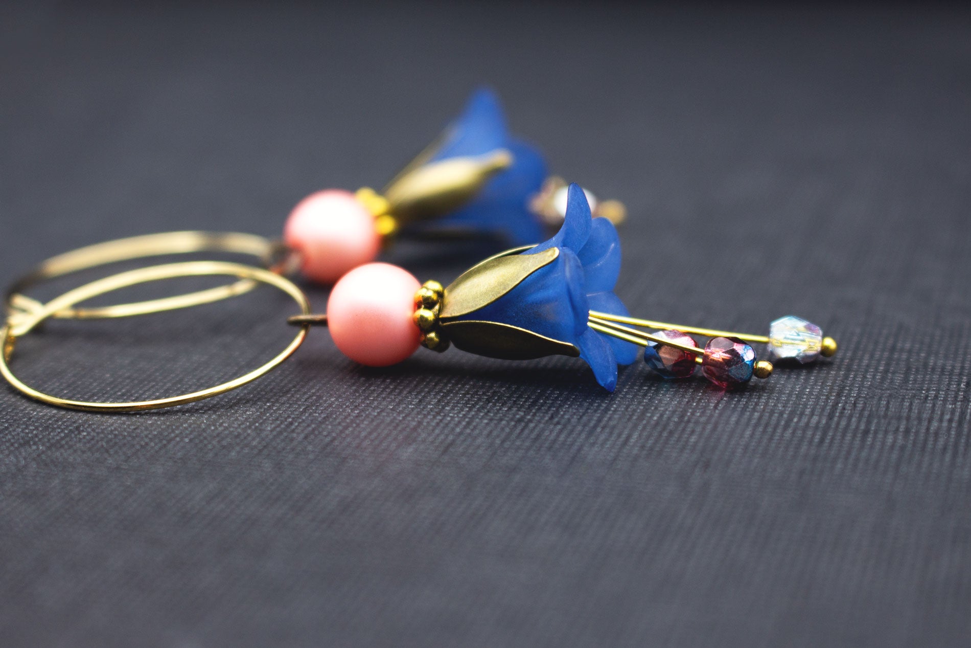 Seitenansicht von Creolen in Gold mit dunkelblauen Blüten und rosa Glasperlen