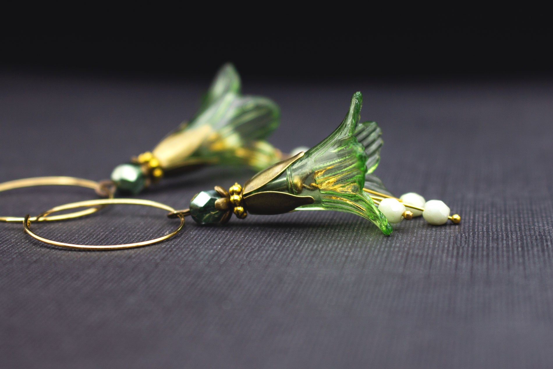 Detailansicht goldfarbener Creolen Ohrringe mit grüner Acrylblüte und lindgrünen Glasperlen