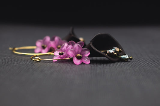 Goldfarbene Creolen mit schwarzer Acrylblüte, Glasperlen in Blau und kleinen lila Blüten – Vorderansicht